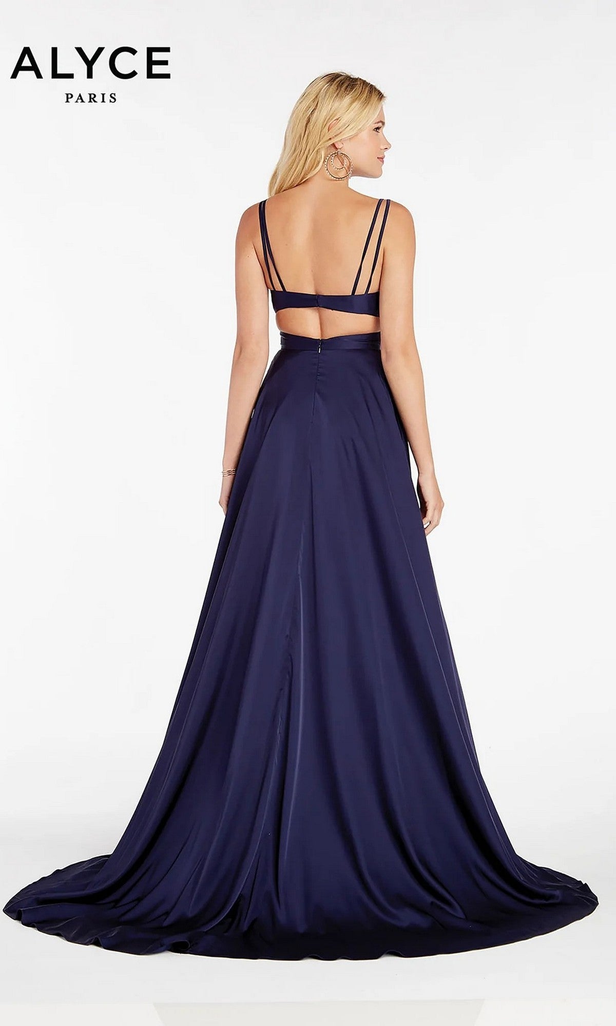 A woman faces away from the camera in the Alyce 60453, a navy blue satin evening gown with double spaghetti straps, an open back, and a long flowing train for an elegant look.